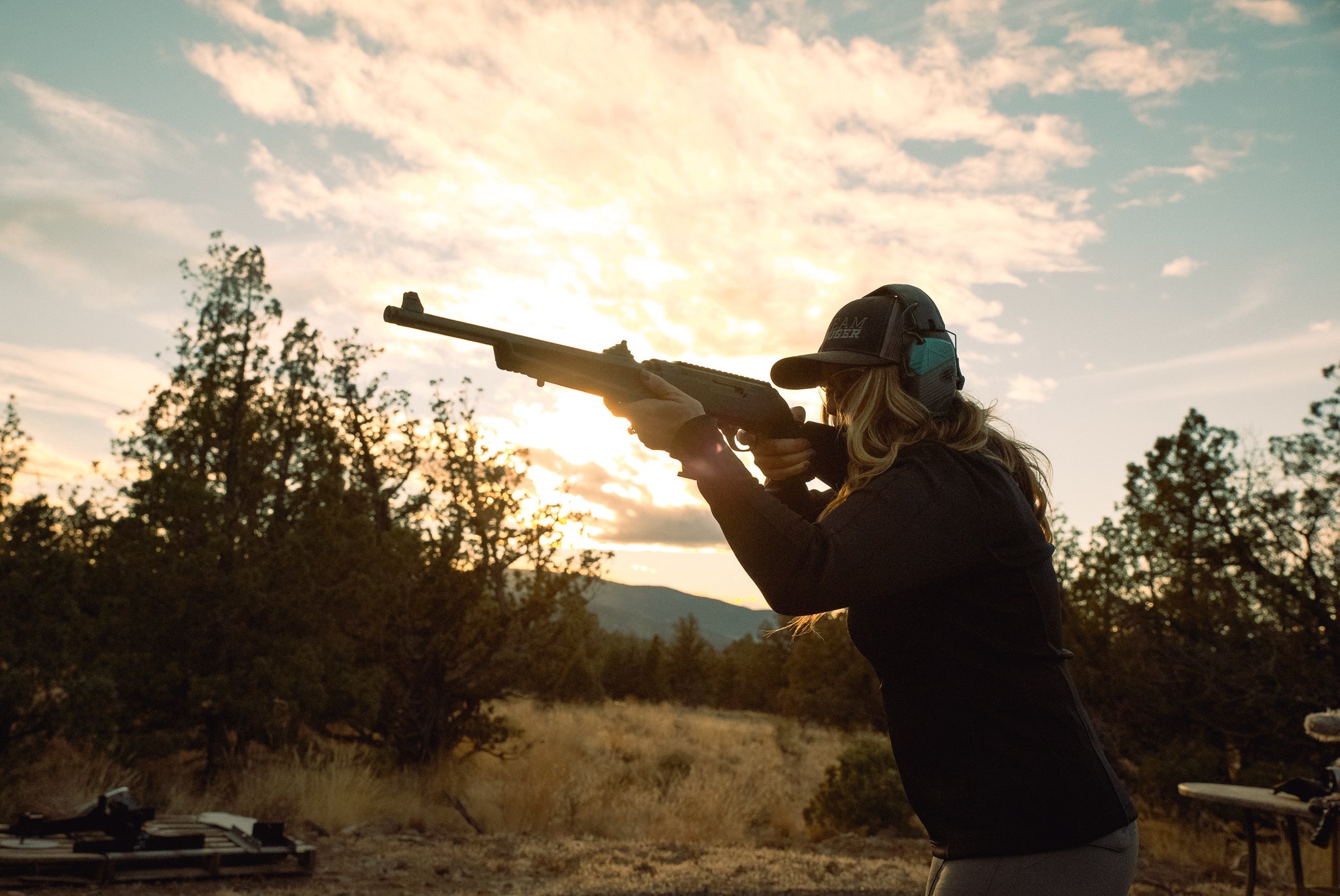 woman hunting with gun at sunset 